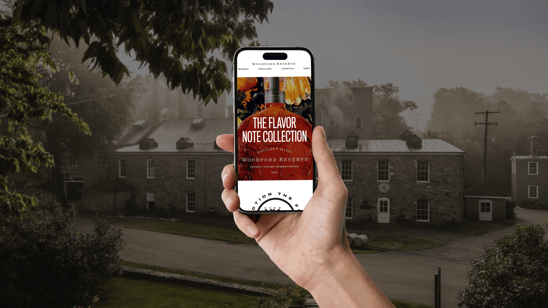 Hand holding smartphone displaying Flavor Note Collection mobile site with Woodford Reserve distillery in background