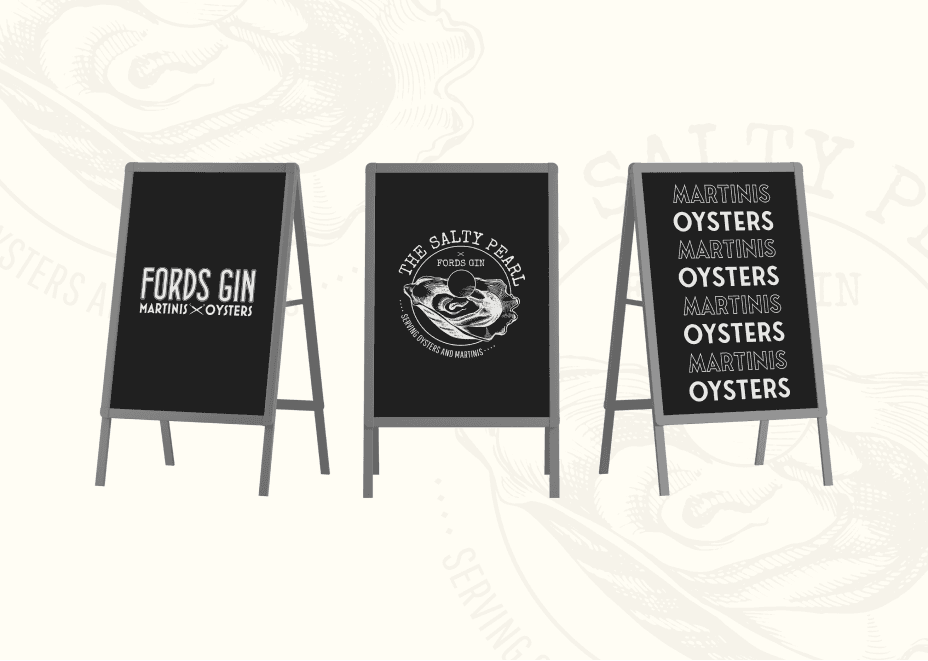 Chalkboard A-frame signs displaying Ford’s Gin branding, The Salty Pearl oyster logo, and alternating Martinis Oysters typography