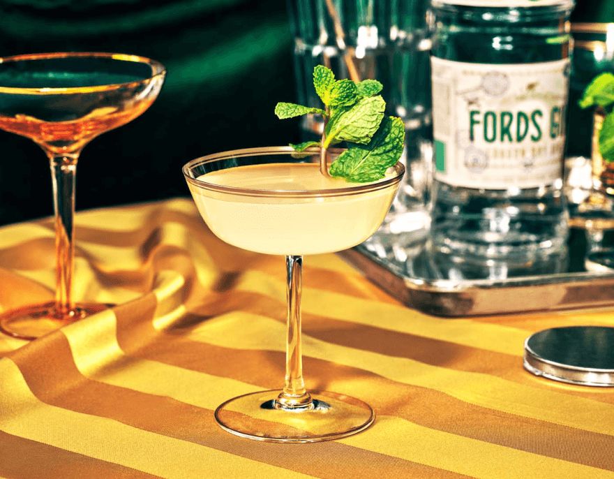Hero product shot featuring a Ford’s Gin cocktail in a coupe glass with mint garnish against a striped backdrop