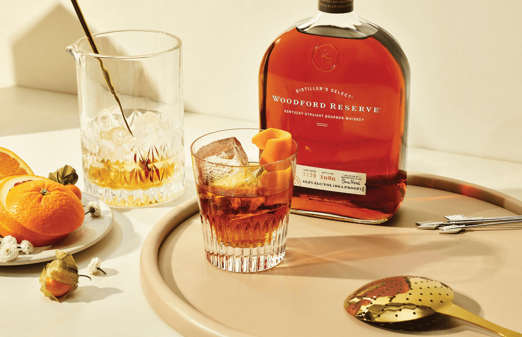 Woodford Reserve bourbon bottle and Old Fashioned cocktail styled with citrus and garnishes on elegant serving tray