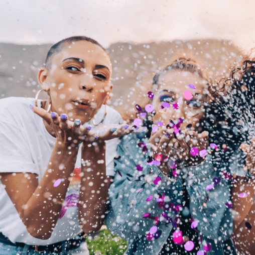 Two people blowing confetti at a community event