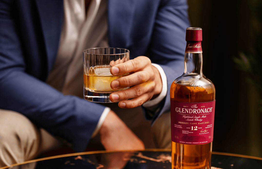 Lifestyle image featuring a hand holding a whisky glass alongside the bottle